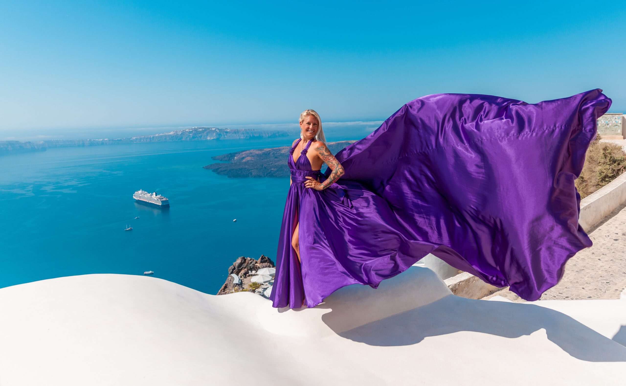 Purple flying dress Santorini photoshoot — elegant silhouette with dramatic fabric in the wind