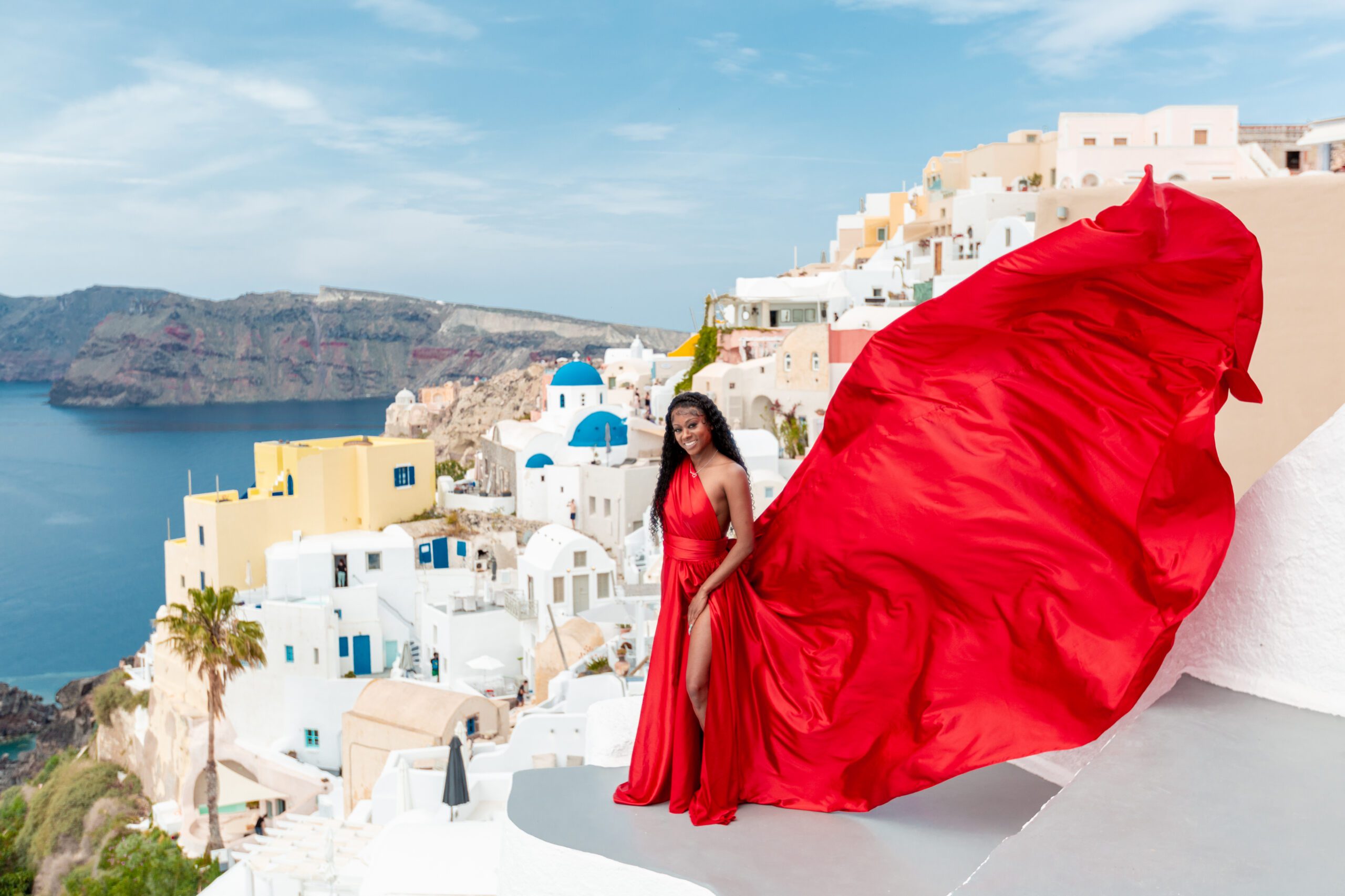 Red flying dress for rent in Santorini — elegant photoshoot in Oia with white-washed walls